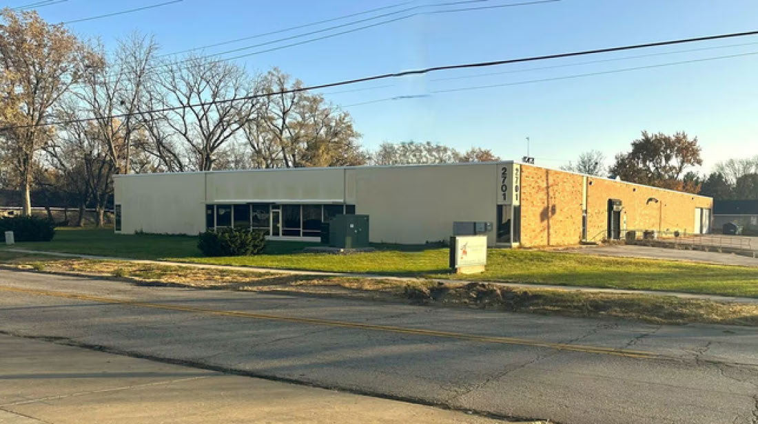 Single-story commercial building with an address of 2701 marked on the brick facade, situated next to a street.